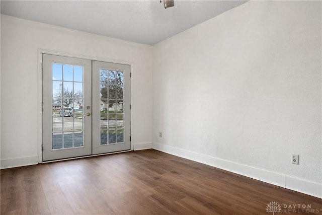 spare room featuring french doors, dark wood-type flooring, and baseboards