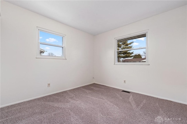 carpeted spare room with visible vents and baseboards