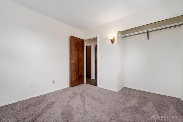 unfurnished bedroom featuring a closet, baseboards, and carpet flooring