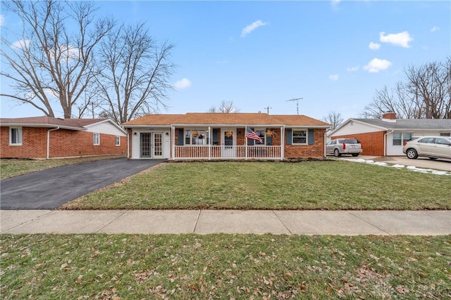 single story home with driveway, covered porch, brick siding, and a front yard