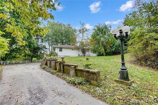 view of yard featuring fence and aphalt driveway