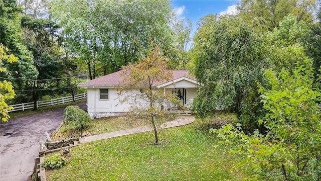 view of front of property with driveway, fence, and a front yard