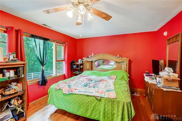 bedroom with ceiling fan, wood finished floors, and visible vents