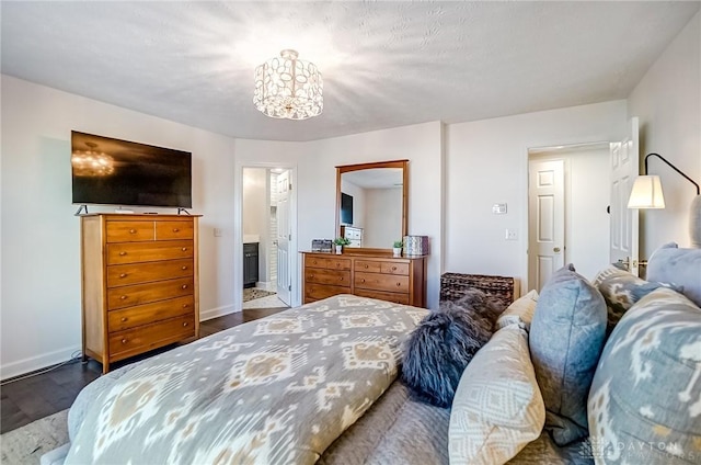 bedroom featuring dark wood-type flooring, a notable chandelier, baseboards, and ensuite bathroom