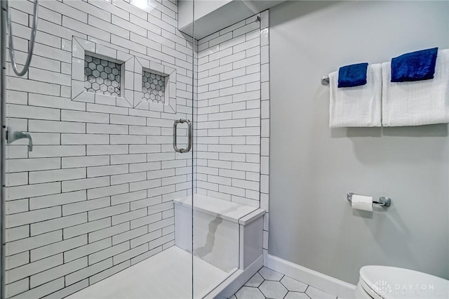 bathroom with tile patterned flooring, a shower stall, toilet, and baseboards