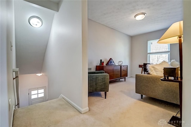 living area with light carpet, a textured ceiling, and baseboards