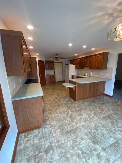 kitchen with baseboards, light countertops, a peninsula, and decorative backsplash