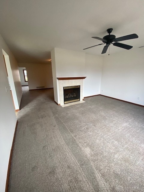 unfurnished living room with carpet flooring, a tile fireplace, visible vents, and baseboards