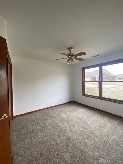 empty room featuring a ceiling fan, carpet, visible vents, and baseboards