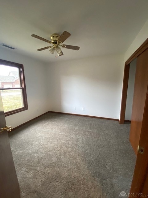 empty room featuring a ceiling fan, baseboards, visible vents, and carpet flooring