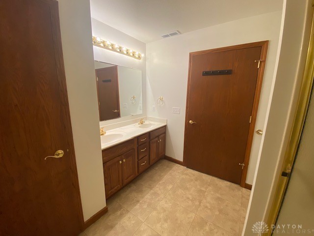 bathroom with visible vents, a sink, baseboards, and double vanity