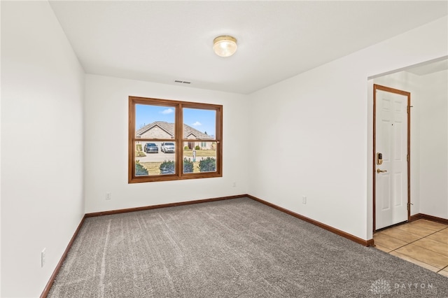 tiled spare room featuring carpet flooring, baseboards, and visible vents