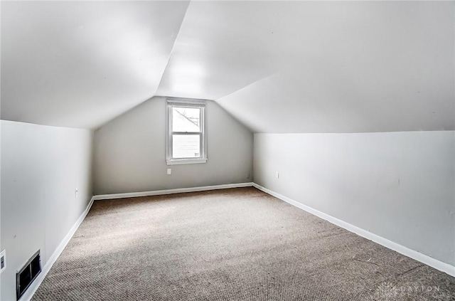 additional living space with vaulted ceiling, carpet, visible vents, and baseboards