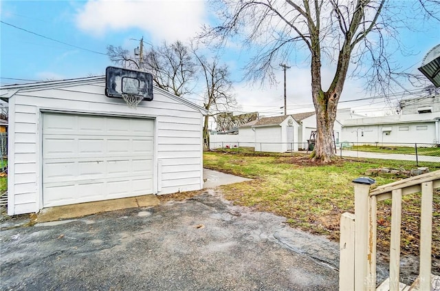 detached garage featuring aphalt driveway and fence