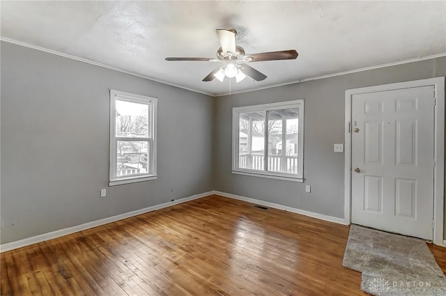 entryway with wood-type flooring, visible vents, ornamental molding, ceiling fan, and baseboards