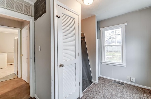 hall with baseboards, visible vents, and carpet flooring