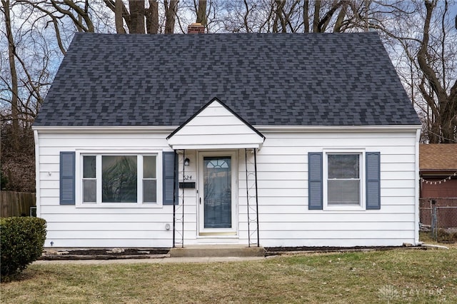 view of front of home with a chimney, roof with shingles, and a front yard