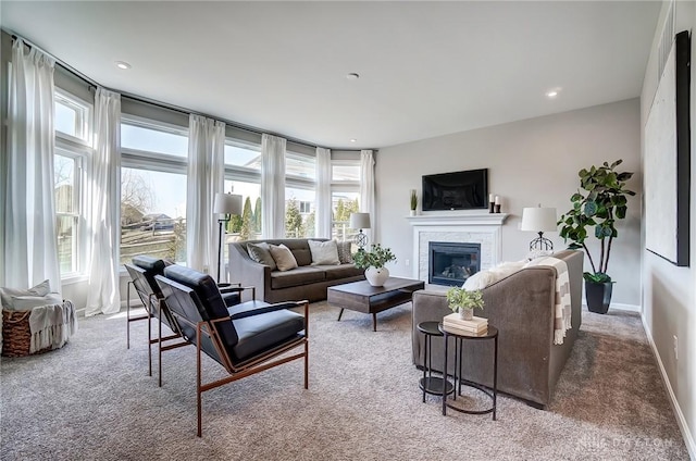 living room featuring baseboards, plenty of natural light, carpet, and a glass covered fireplace