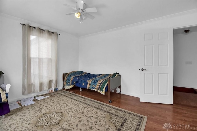 bedroom featuring a ceiling fan, baseboards, ornamental molding, and wood finished floors