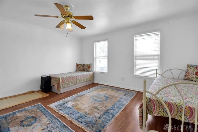 bedroom with a ceiling fan, baseboards, and wood finished floors