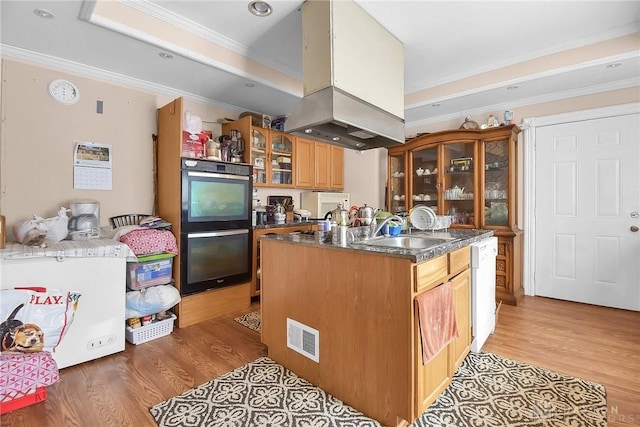 kitchen with dishwasher, ornamental molding, light wood-type flooring, and a kitchen island with sink