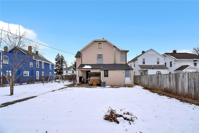 snow covered house featuring a fenced backyard