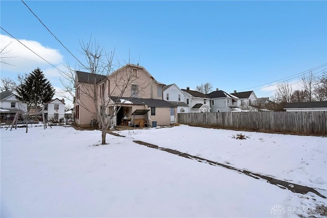 snow covered property featuring a residential view and fence