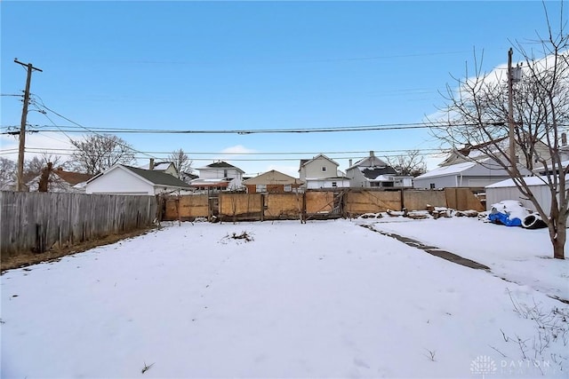 yard layered in snow with a residential view and a fenced backyard