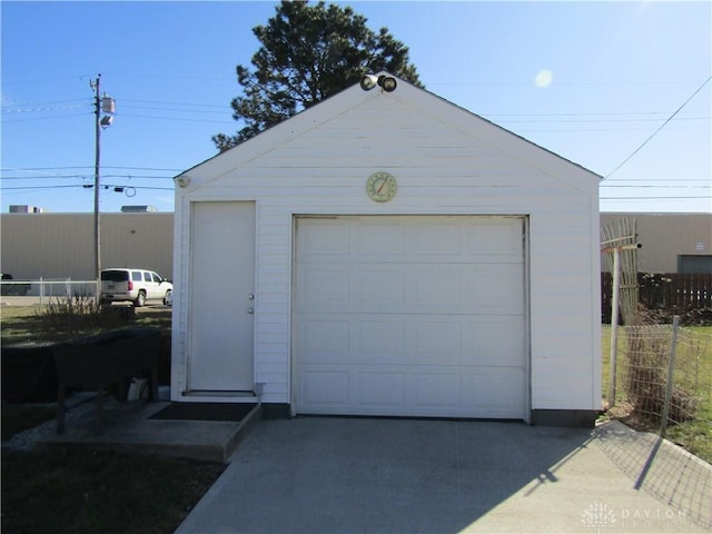 detached garage with concrete driveway and fence