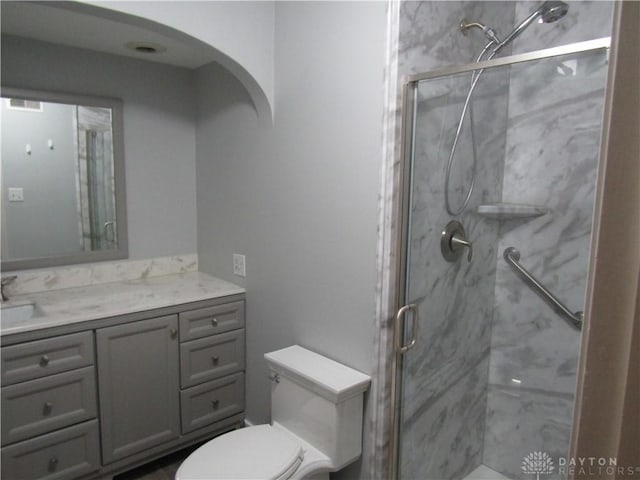 full bath with toilet, vanity, and a marble finish shower