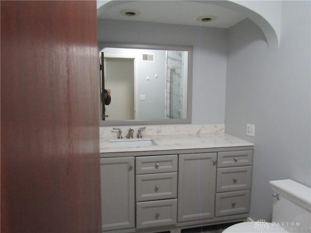 full bath featuring visible vents, a shower with door, vanity, and toilet