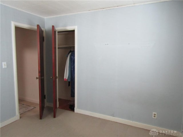 unfurnished bedroom with carpet, a closet, and baseboards