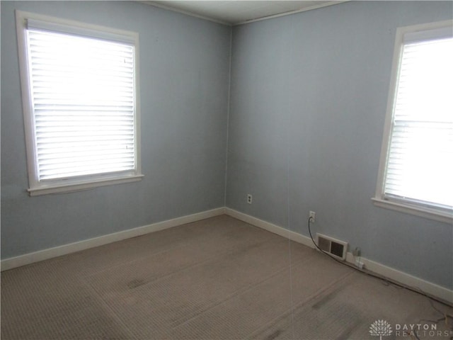 unfurnished room with visible vents, light carpet, and baseboards