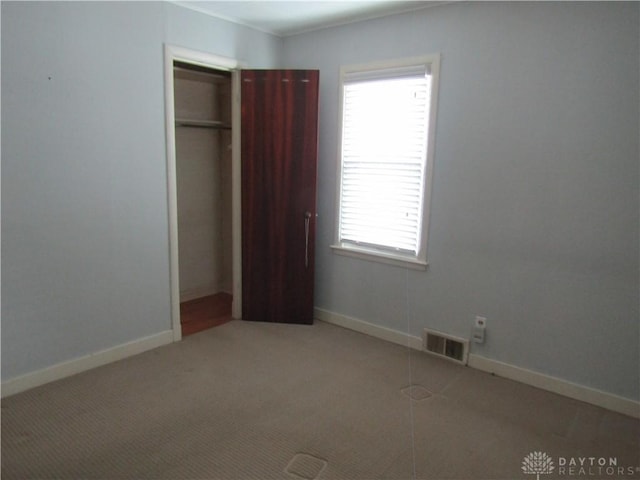 unfurnished bedroom featuring baseboards, visible vents, a closet, and light colored carpet