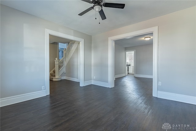 spare room featuring stairs, dark wood-type flooring, and baseboards