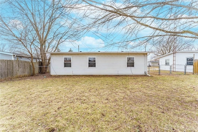 back of house featuring a fenced backyard, a gate, and a lawn