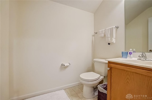 half bath with tile patterned flooring, toilet, vanity, baseboards, and vaulted ceiling