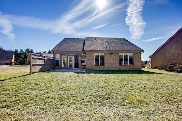 back of house with brick siding, a yard, and french doors