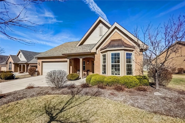 view of front of house featuring driveway, roof with shingles, an attached garage, a porch, and brick siding