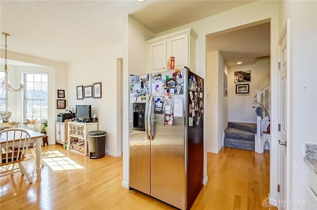 kitchen featuring a chandelier, white cabinetry, light wood-type flooring, stainless steel fridge, and decorative light fixtures