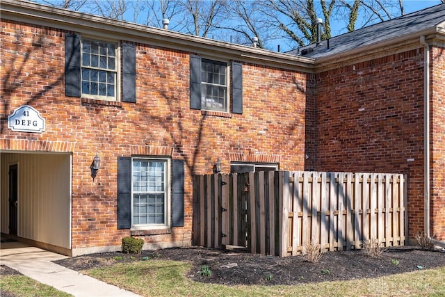 view of property exterior with brick siding and fence