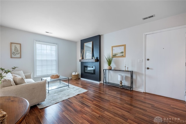 living room featuring a fireplace, wood finished floors, visible vents, and baseboards