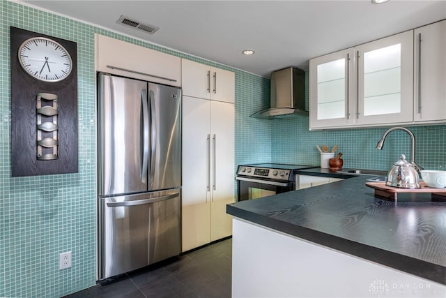 kitchen with visible vents, dark countertops, wall chimney exhaust hood, stainless steel appliances, and a sink