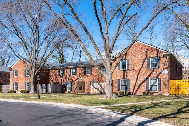 view of front of property with fence, a front lawn, and brick siding