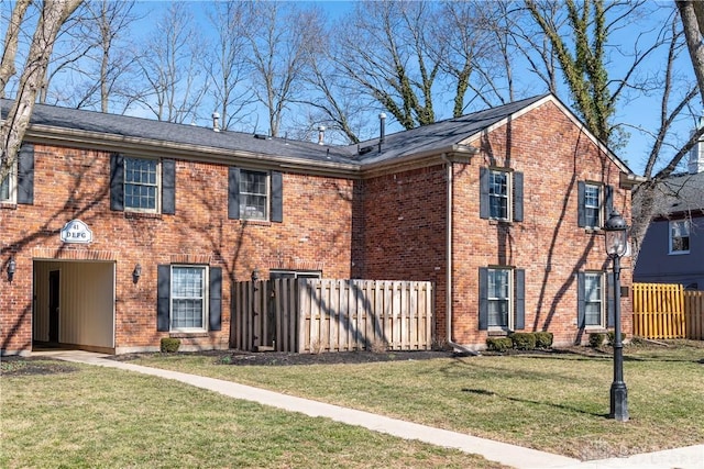 view of front of home with a front yard, fence, and brick siding