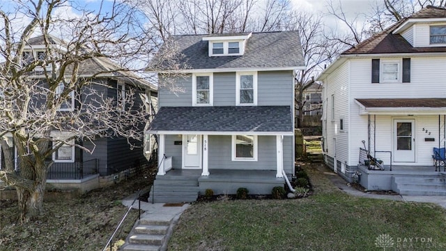 traditional style home featuring a porch, roof with shingles, and a front lawn