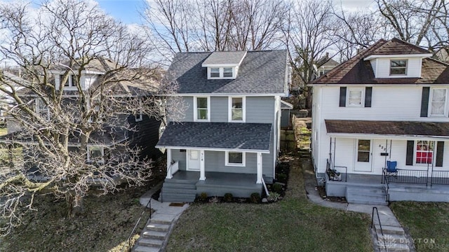 view of front of home with a shingled roof, covered porch, and a front lawn