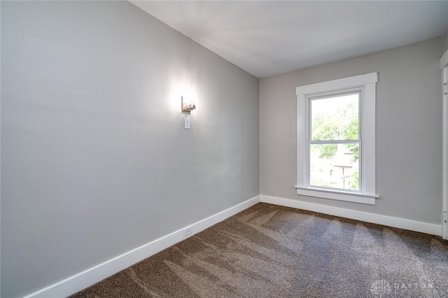 unfurnished room with dark carpet and baseboards