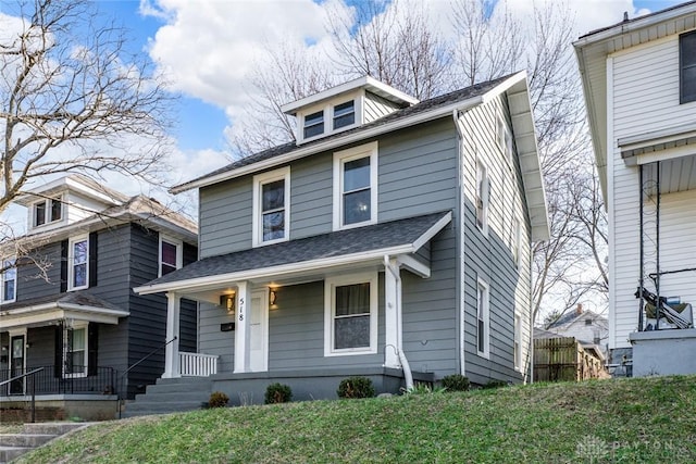 traditional style home with covered porch and a shingled roof