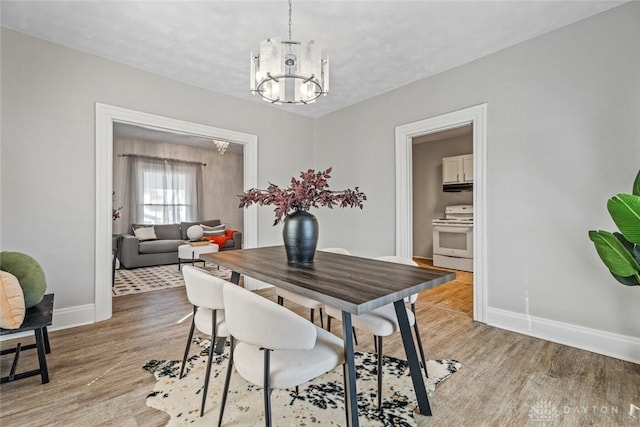 dining area with baseboards, a chandelier, and light wood-style floors